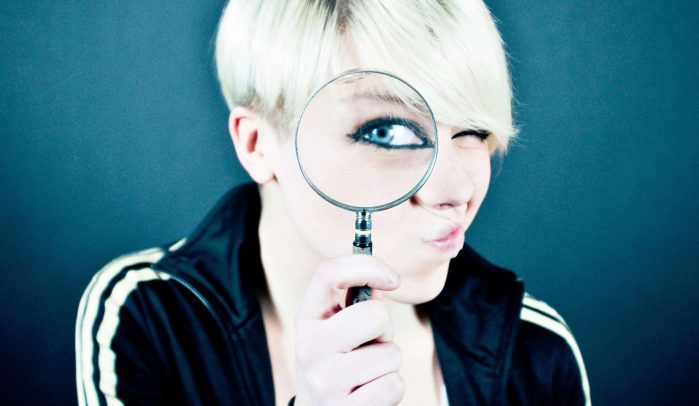 Woman-with-short-blond-hair-looking-through-a-magnifying-glass