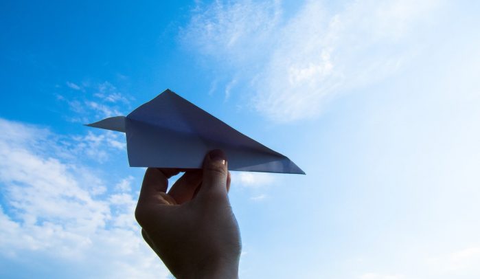 Hand-launching-paper-plane-into-blue-sky