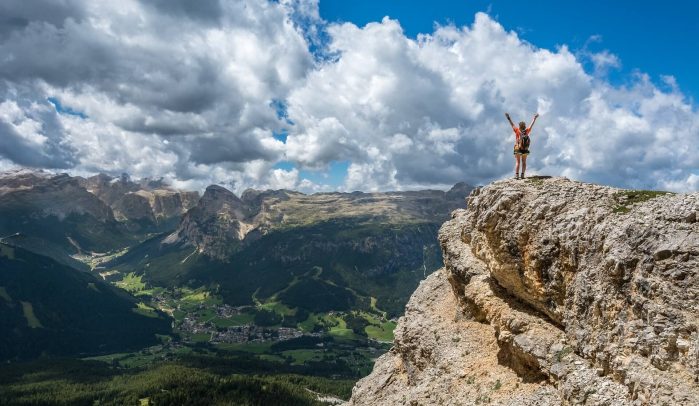 Woman-with-arms-in-the-air-standing-on-top-of-a-mountain