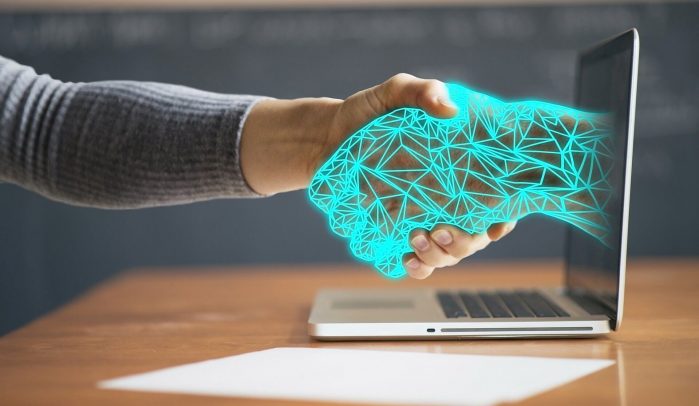 Human-hand-shaking-computerised-hand-coming-out-of-a-laptop-screen