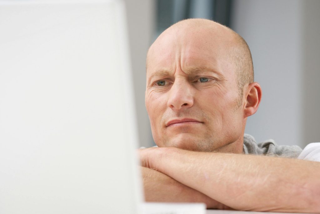 Man-staring-impatiently-at-laptop