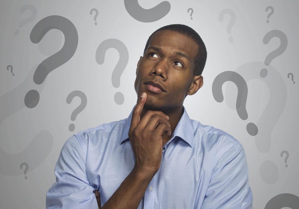 Man thinking against background of question marks