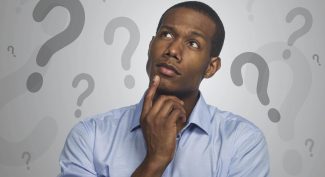 Man thinking against background of question marks