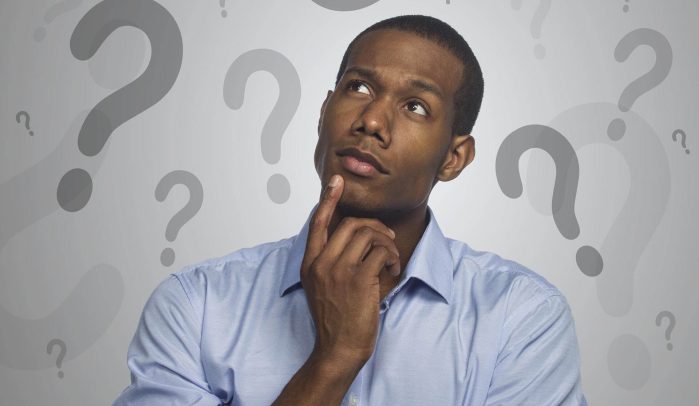 Man thinking against background of question marks