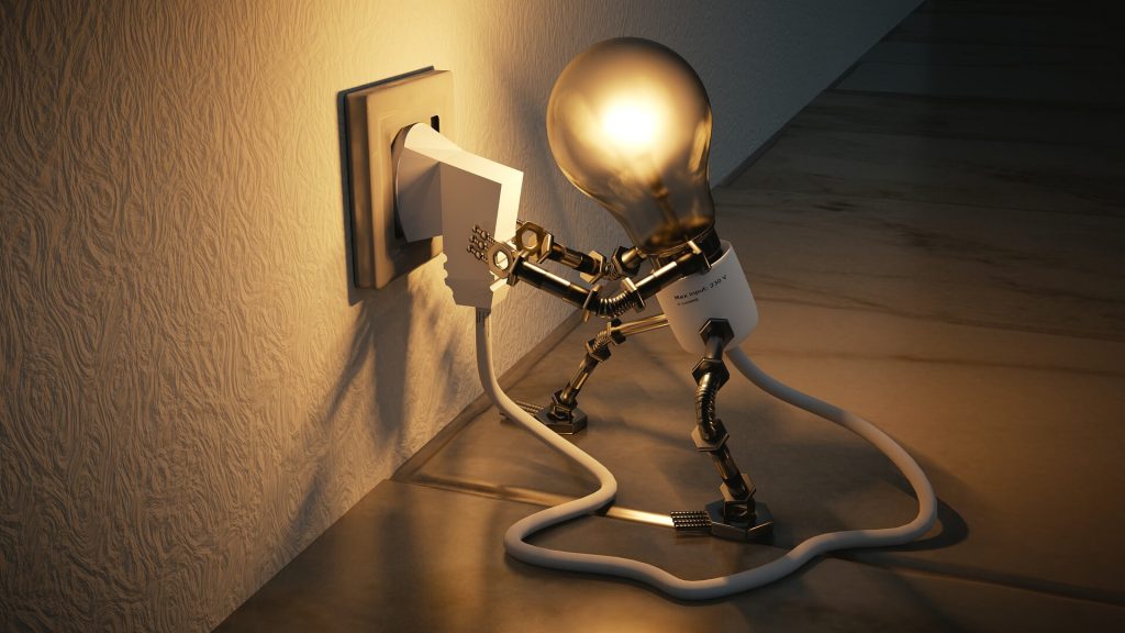 Lit lightbulb man plugging himself into an electric wall socket