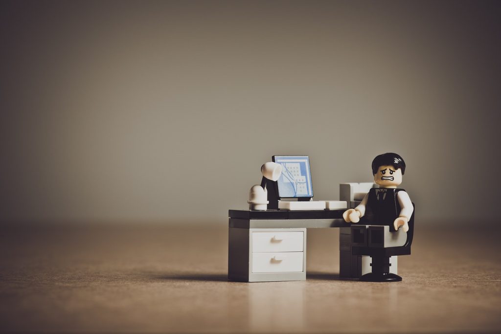 Lego businessman sitting at his computer with a despairing expression