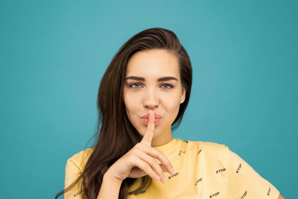 Woman-with-finger-over-lips-on-blue-background