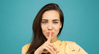 Woman-with-finger-over-lips-on-blue-background