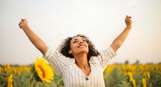 Woman-standing-triumphantly-with-arms-in-the-air-in-sunflower-field
