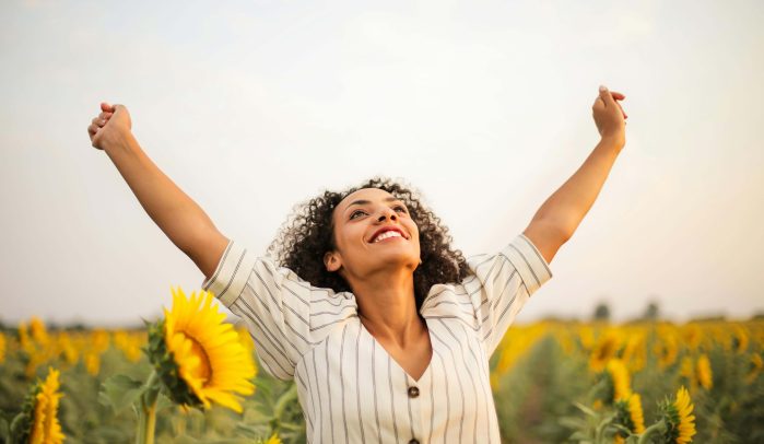 Woman-standing-triumphantly-with-arms-in-the-air-in-sunflower-field