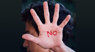 Man-holding-his-open-hand-towards-the-camera-the-word-NO-is-written-on-his-palm-in-red.